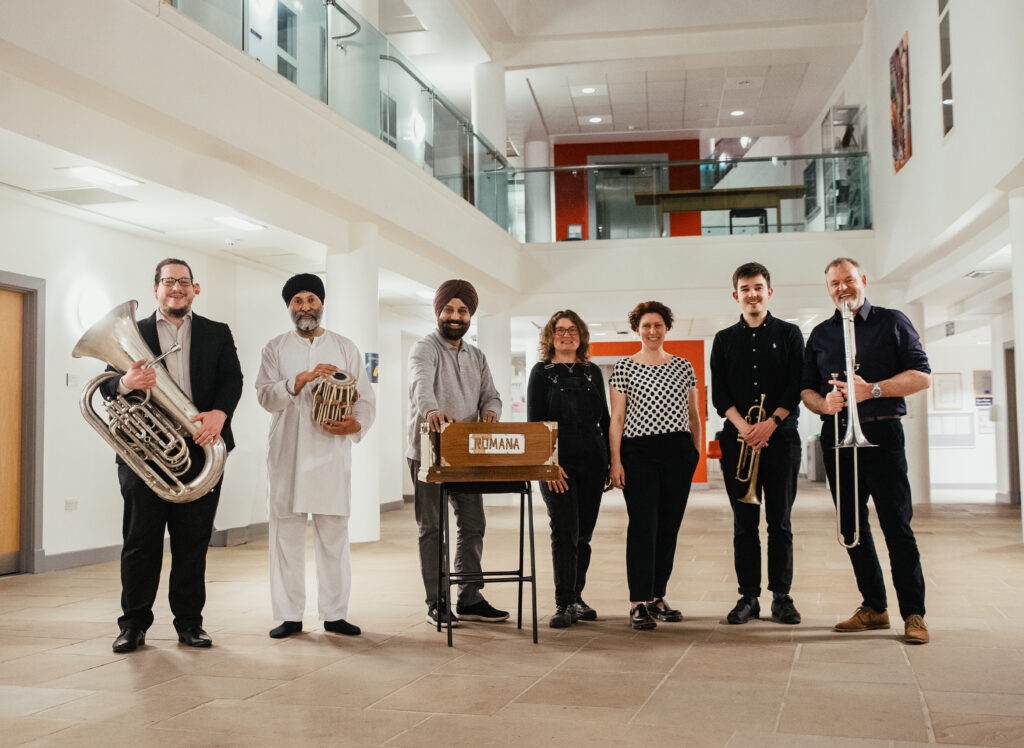 A group of people with brass instruments, tabla and harmonium