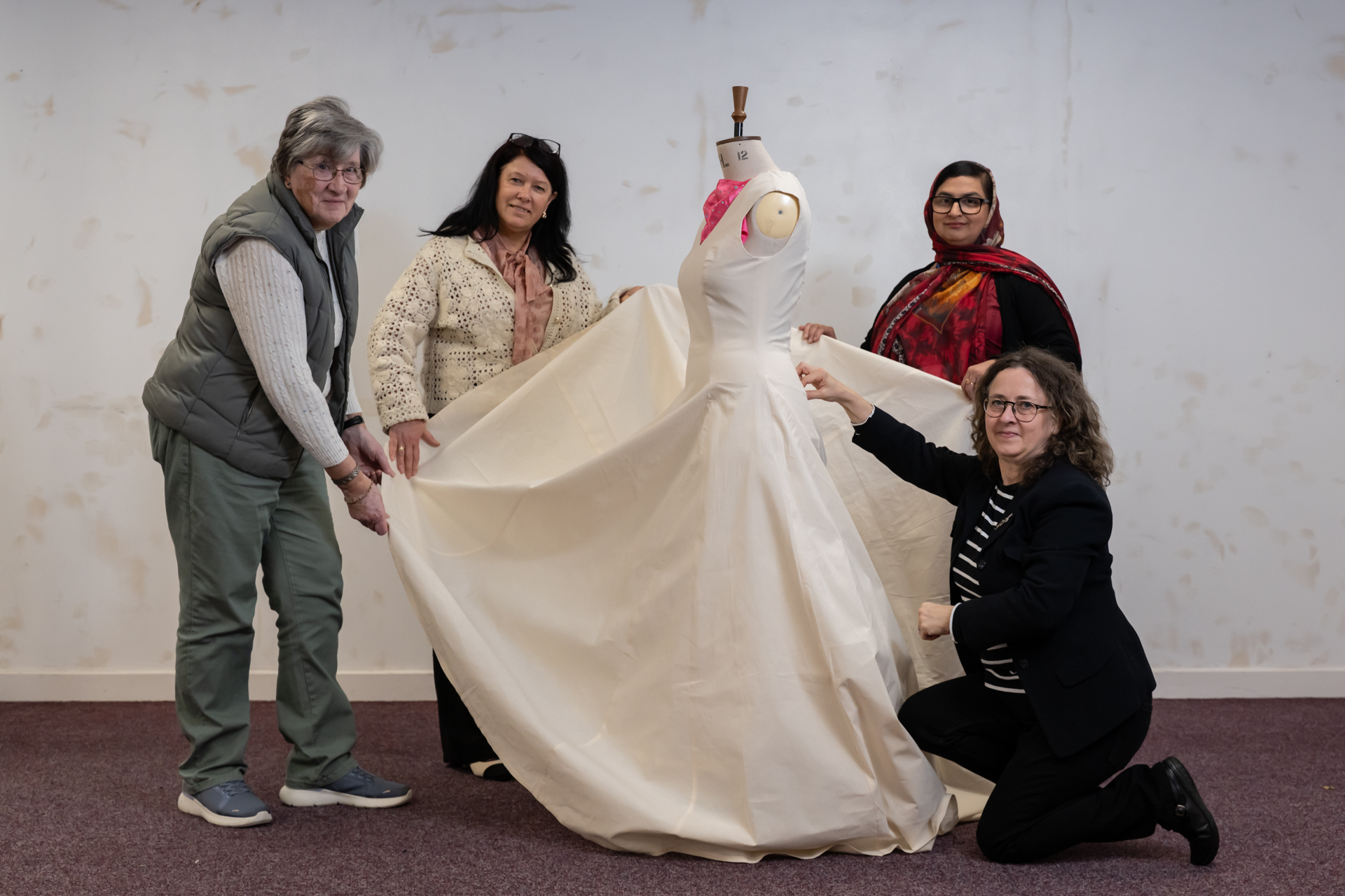 5 people holding out a Calico Dress displayed on a mannequin