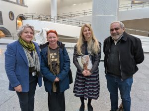 Four people standing in a row smiling