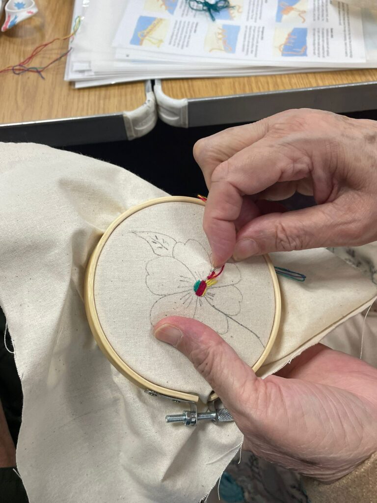 A close up of hands embroidering on a hoop