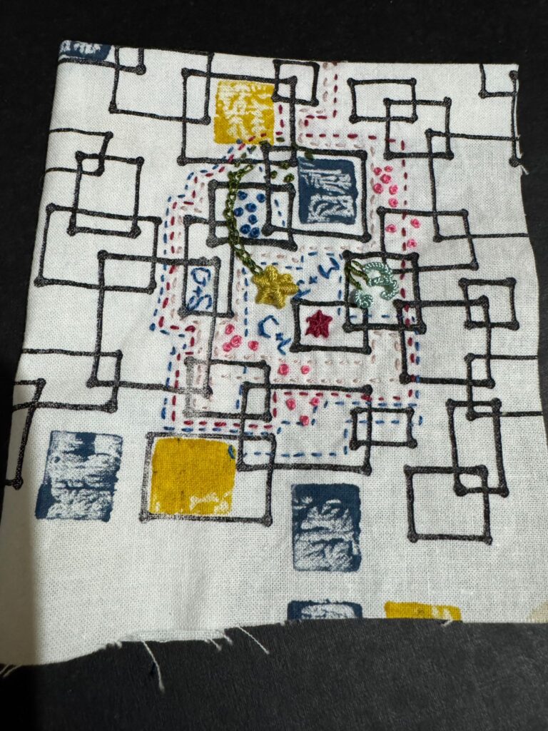 A handmade embroidered textile patch with a rectangles and running stitches