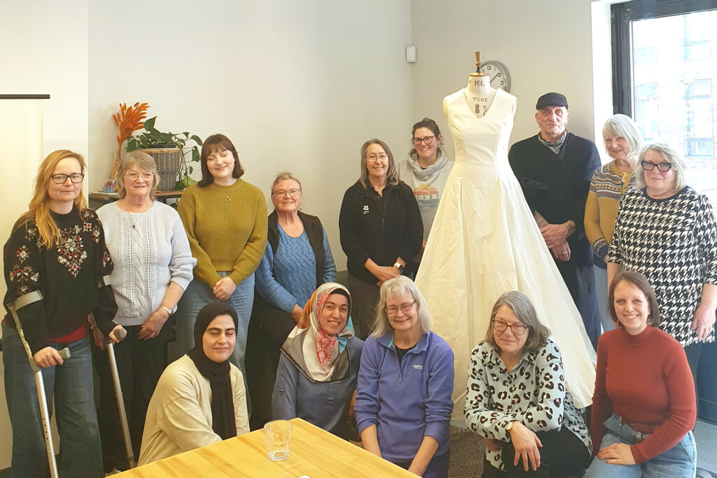 A group of people posing next to a Calico Dress on a mannequin